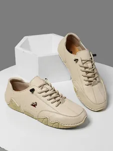 Primer plano de zapatos casuales beige con logo de cabra y cordones elásticos negros