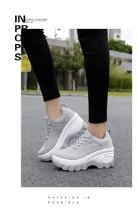 Detailed outdoor shot showing the textured mesh upper and thick platform sole of grey sneakers
