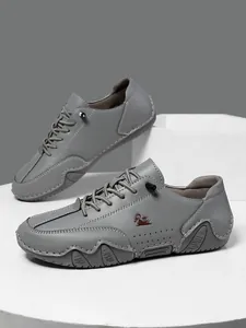 Detalle de zapatos casuales de cuero gris con logo de cabra roja y suela de goma ondulada