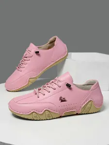 Primer plano de zapatillas de cuero rosa con perforaciones laterales y logo de carnero