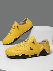 Detalle de zapatos casuales de cuero amarillo con logo de cordero y suela ondulada
