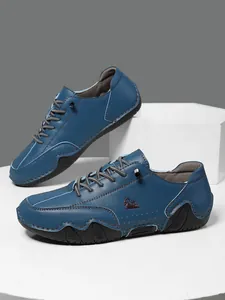 Detalle de zapato casual de cuero azul con logo de carnero en relieve y costuras blancas