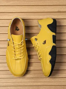 Detalle de mocasines de cuero amarillo con suela de goma antideslizante y logo lateral