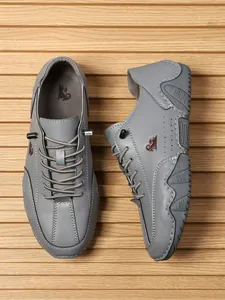 Detalle de zapatos informales grises para hombre con logo de carnero y costuras blancas