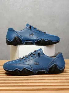 Detalle macro de zapatos de cuero azul oscuro con perforaciones laterales decorativas