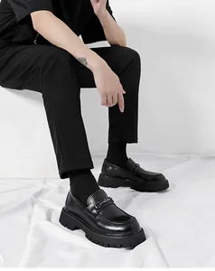 Close-up of black platform loafers with glossy patent leather and metal horsebit detail