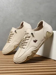 Detalle de zapatos informales de cuero beige con logo de oveja y suela de caucho