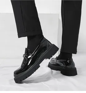 Detail of glossy patent leather loafers featuring a metal horsebit and chunky lug sole