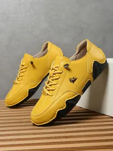 Detalle de zapato casual de cuero amarillo con logo de cabeza de carnero y suela de goma negra