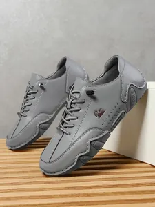 Detalle de zapatos casuales de cuero gris con logo de cabra bordado y punta cosida a mano