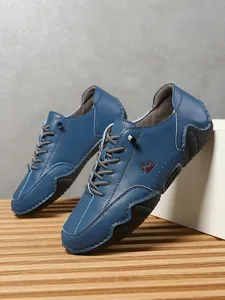 Detalle de mocasines de cuero azul con costuras en contraste y suela de goma con relieve