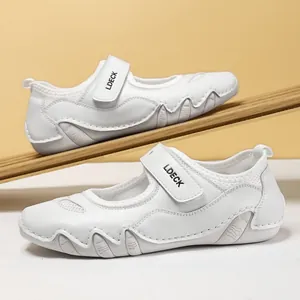 Primer plano de zapatos casuales de cuero blanco con cierre de velcro en madera