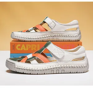 Detail of white leather sandals with orange-green cross straps and hook-and-loop closure