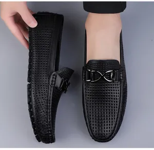 Detail van zwarte lederen loafer met uitgesneden textuur en metalen gesp decoratie