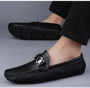 Detail van zwarte geperforeerde leren loafers voor heren met zilveren gesp en rubberen zool