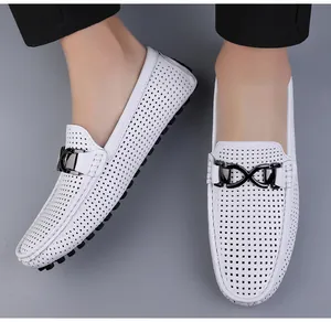 Detail van witte lederen loafers met gatenpatroon, rubberen zool en metalen gesp