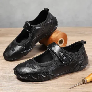 Detalle de zapato Mary Jane de cuero negro con cierre de velcro en mesa de artesanía