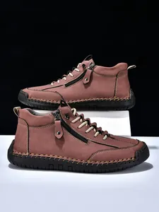 Detailed close-up showing manual stitching and side zipper on brown leather men's boots