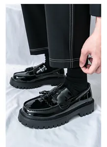 Gros plan de mocassins à plateforme noirs avec glands et finition en cuir verni brillant