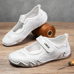 Vista detallada de zapatos Mary Jane de cuero blanco con velcro sobre superficie de madera