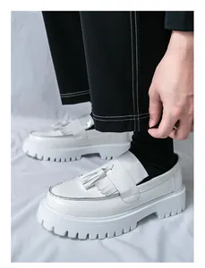 Gros plan de mocassins à plateforme blancs avec glands, fini brillant et semelle épaisse