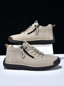 Detailed close-up of men's beige suede boots featuring side zipper and hand-stitched seams