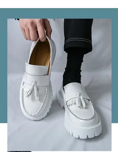 Détail de mocassins en cuir verni blanc avec glands et semelle plateforme crantée