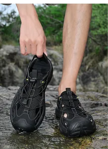 Men's black outdoor hiking sandals with quick-lace system and protective toe cap on rocks