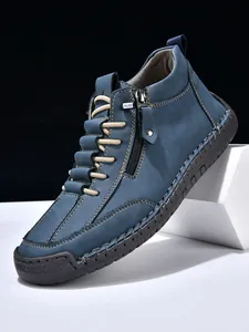 Detailed view of blue leather boots with side zipper and thick gray rubber sole