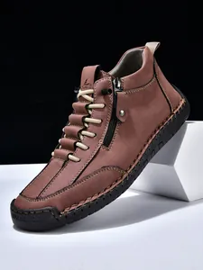 Detail of men's brown leather boots with side zipper, elastic laces and contrast stitching