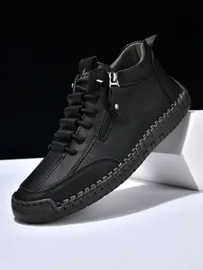 Close-up of black leather boots with side zipper, hand-stitched sole and lace-up details