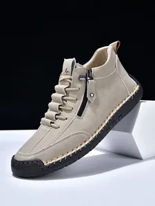 Detailed view of beige men's Martin boots with side zipper and contrast hand stitching