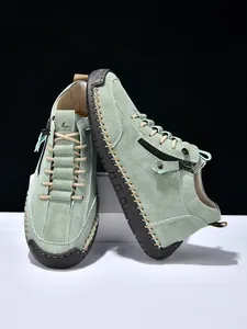 Close-up of suede men's casual boots featuring thick hand-stitching and side zipper detail