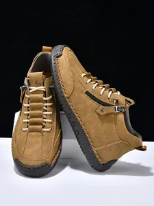 Detail of dark tan men's ankle boots showing matte texture, metal zipper and stitching