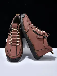 Detailed view of men's brown leather boots with side zipper and rugged stitching