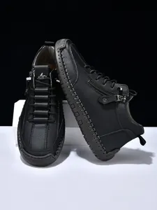 Detail of black leather boots with side zipper and distinct handmade stitching craft