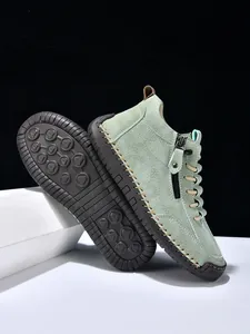 Detail of mint green suede boots with side zipper, handmade stitching, and rubber sole