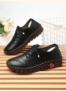 Detail of black leather loafers featuring hand-stitched weaving and a cartoon logo accent