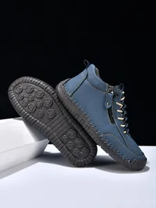 Detail of blue suede men's boots showing stitching, metal zipper, and rubber sole grip