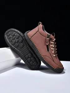Detailed close-up of men's leather boots showing side zippers and non-slip rubber soles