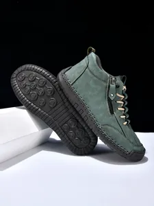Close-up of men's teal suede boots featuring side zippers and hand-stitched details