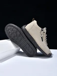 Detail of men's casual beige suede boot showing side zipper and hand-stitched sole