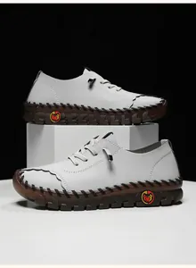 Close-up of light grey litchi leather texture and black hand-stitched details on the shoe
