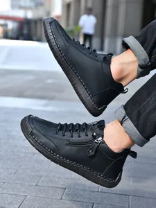 Detailed view of black leather men boots with contrast stitching and side zipper