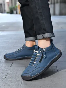Detail of blue suede leather boots featuring side zipper and hand-stitched craftmanship