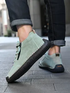 Close-up of sage green men's casual boots with decorative stitching and side zipper