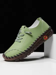 Close-up of green leather loafer featuring white stitching and woven rope detailing