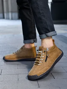 Detail of men's tan leather casual boots showing lacing and side zipper on a person
