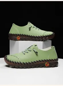 Close-up of handmade green leather loafers featuring black stitching and thick brown soles
