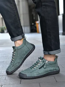 Close-up of men's leather boots with detailed contrast stitching and side zipper